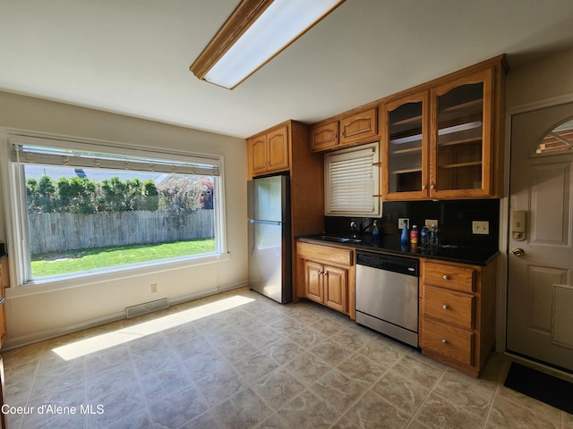 607 W Riverside Ave, Kellogg, ID 83837 - kitchen with appliances with stainless steel finishes, dark countertops, brown cabinets, glass insert cabinets, and a sink