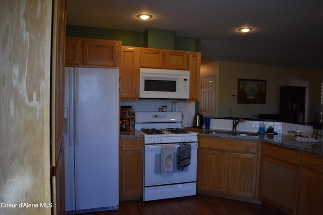 1406 Walnut, Sandpoint, ID 83864 - kitchen featuring white appliances, a sink, dark stone counters, dark wood-style flooring, and brown cabinetry