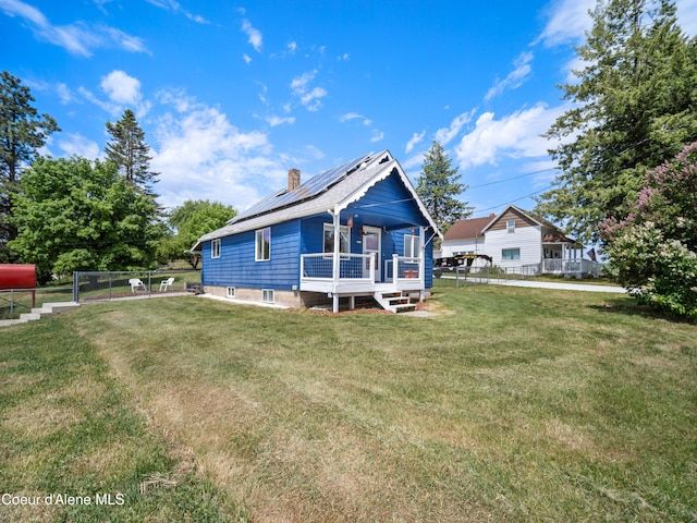 409 N 2nd St, Fairfield, WA 99012 - back of house featuring roof mounted solar panels, a chimney, and a deck