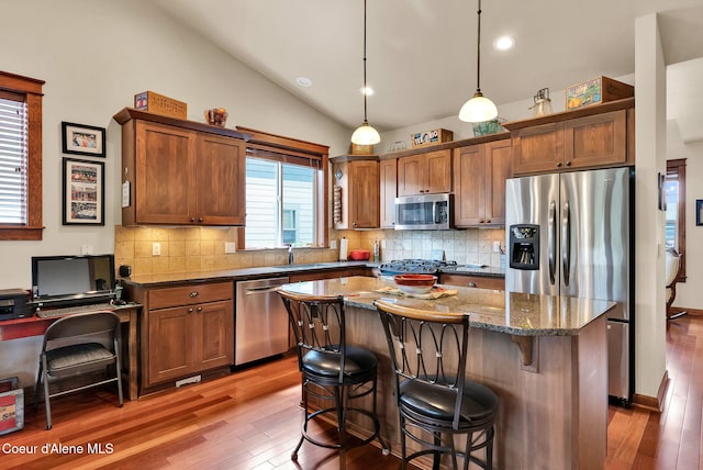 14774 N Pristine Cir, Rathdrum, ID 83858 - kitchen with stainless steel appliances, hardwood / wood-style flooring, a kitchen breakfast bar, dark stone counters, and lofted ceiling