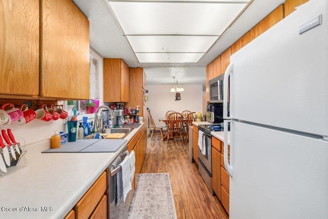 201 S Sequoia Ct, Post Falls, ID 83854 - kitchen featuring appliances with stainless steel finishes, a sink, light countertops, light wood finished floors, and brown cabinets