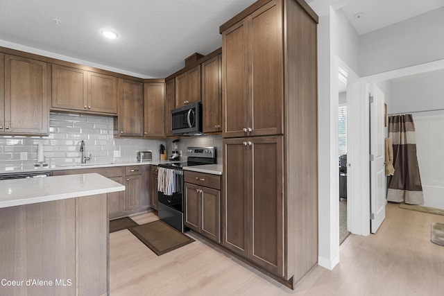 6430 N Atlas Rd Unit 101, Coeur Dalene, ID 83815 - kitchen featuring appliances with stainless steel finishes, a sink, light wood finished floors, tasteful backsplash, and light countertops