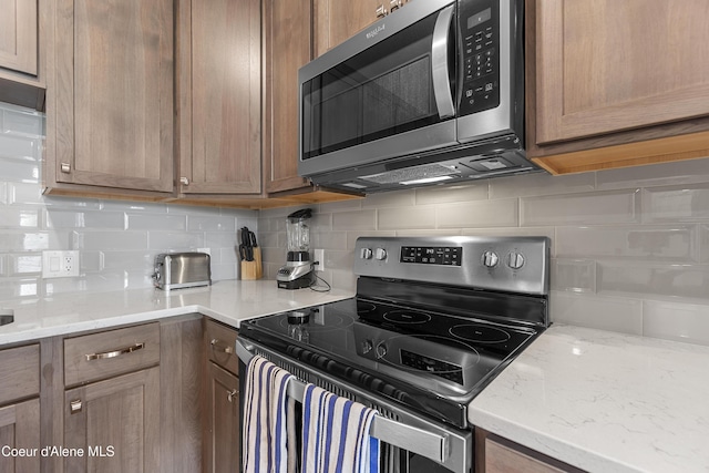 6430 N Atlas Rd Unit 101, Coeur Dalene, ID 83815 - kitchen featuring appliances with stainless steel finishes, decorative backsplash, and light stone counters