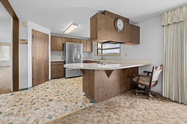 1995 Long Rd, Plummer, ID 83851 - kitchen with stainless steel fridge, a peninsula, light countertops, a sink, and light carpet