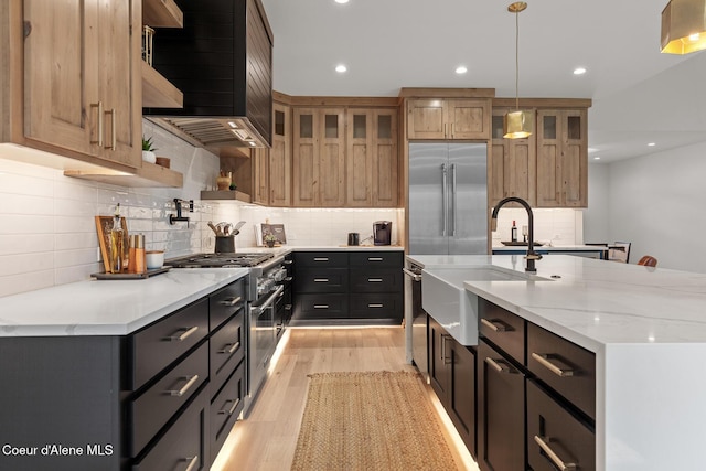 11733 N Blue Jay Loop, Hayden, ID 83835 - kitchen featuring high end appliances, a sink, custom exhaust hood, decorative backsplash, and light wood-type flooring