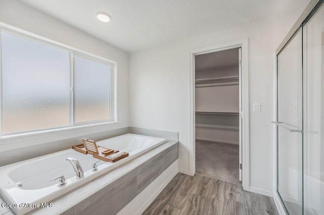 16171 N Hadley Loop, Rathdrum, ID 83858 - bathroom featuring a garden tub, wood finished floors, a spacious closet, and baseboards