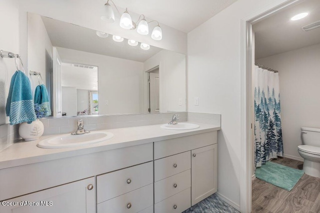 16171 N Hadley Loop, Rathdrum, ID 83858 - full bathroom featuring toilet, wood finished floors, double vanity, baseboards, and a shower with shower curtain