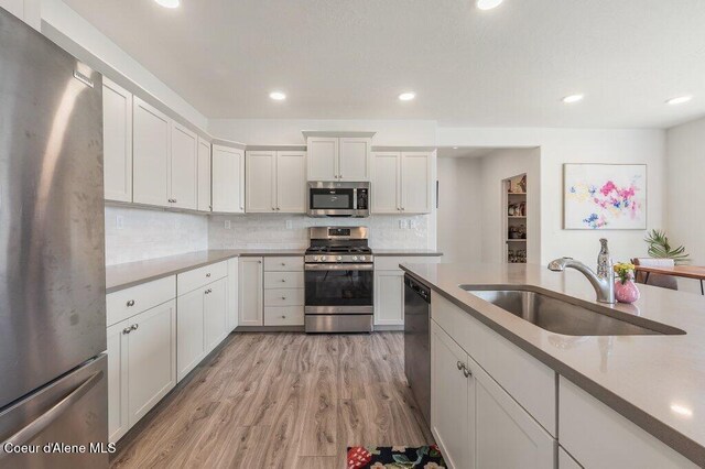 16171 N Hadley Loop, Rathdrum, ID 83858 - kitchen featuring appliances with stainless steel finishes, a sink, light wood finished floors, decorative backsplash, and recessed lighting