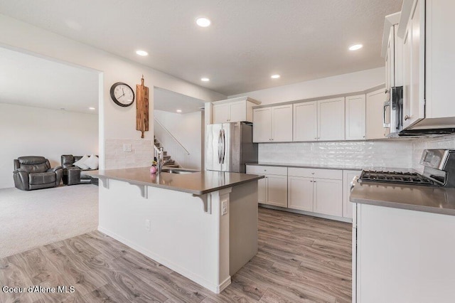 16171 N Hadley Loop, Rathdrum, ID 83858 - kitchen featuring stainless steel appliances, light wood-type flooring, decorative backsplash, recessed lighting, and a kitchen bar