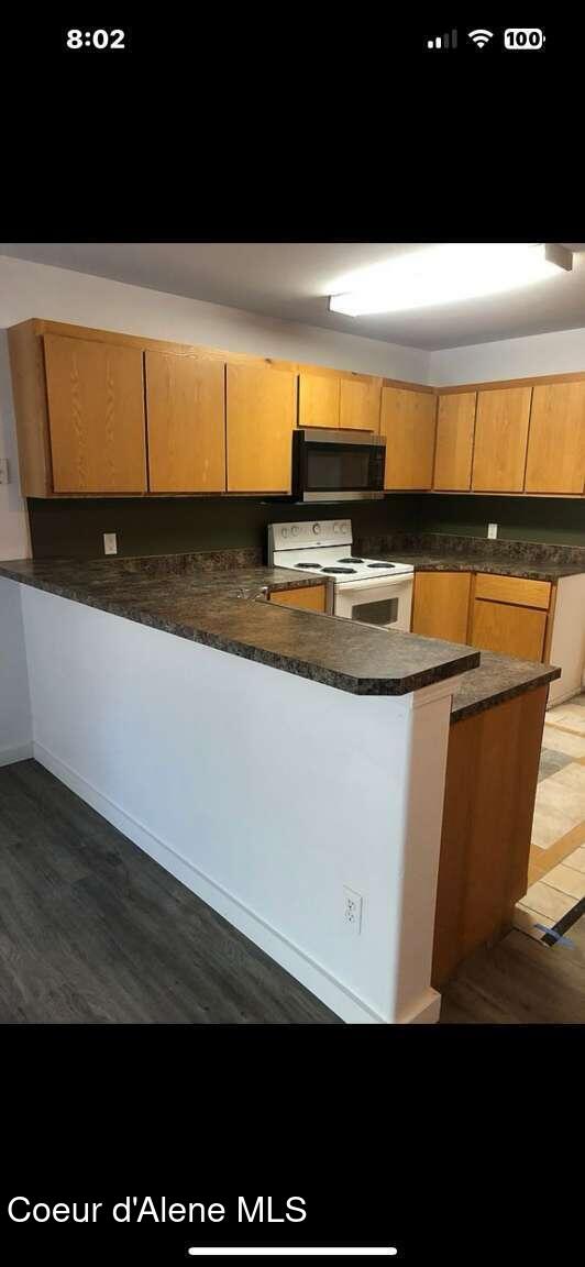 243 Pine St, Moyie Springs, ID 83845 - kitchen featuring white electric range, stainless steel microwave, a peninsula, and dark countertops