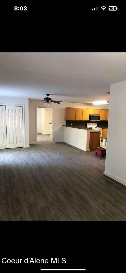 243 Pine St, Moyie Springs, ID 83845 - unfurnished living room featuring ceiling fan, dark wood-style floors, and baseboards