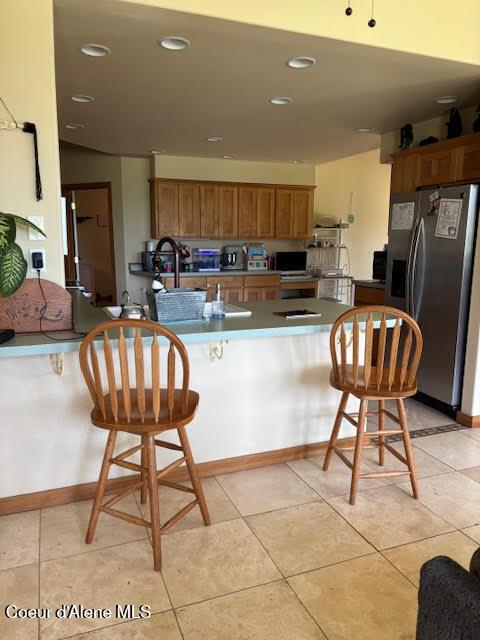 707 Patches Ln, Saint Maries, ID 83861 - kitchen with stainless steel fridge with ice dispenser, brown cabinets, a peninsula, a breakfast bar area, and recessed lighting