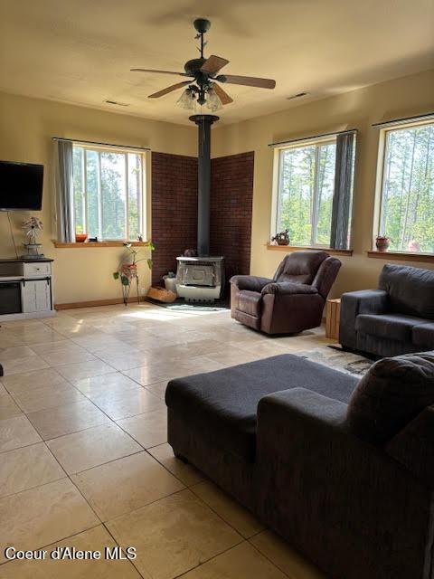 707 Patches Ln, Saint Maries, ID 83861 - living room with light tile patterned floors, a wood stove, and ceiling fan