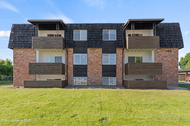107 E Hattie Ave, Coeur Dalene, ID 83814 - view of front facade with brick siding, a front yard, mansard roof, and a balcony