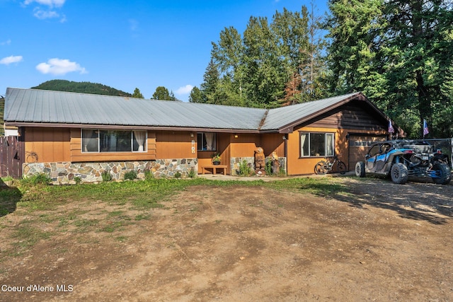 312 E 5th Ave, Clark Fork, ID 83811 - view of front of house featuring a metal roof, driveway, an attached garage, and stone siding