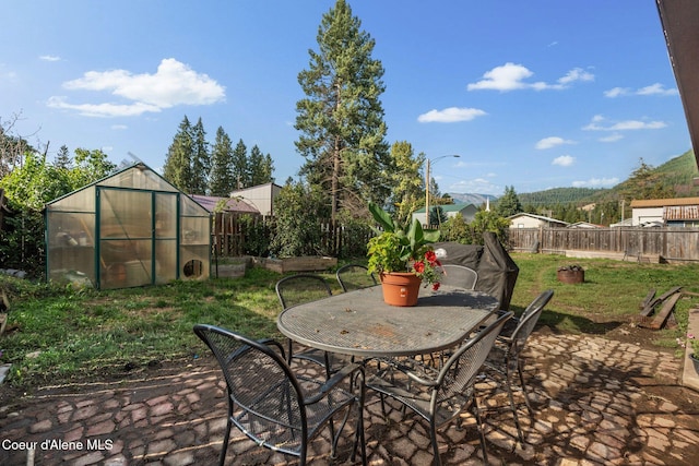 312 E 5th Ave, Clark Fork, ID 83811 - fenced backyard featuring a greenhouse, an outbuilding, a patio, and outdoor dining space