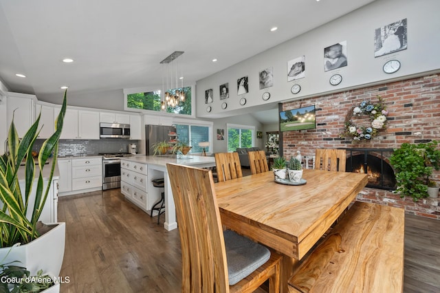 3593 W Fairway Dr, Coeur Dalene, ID 83815 - dining room featuring dark wood-type flooring, a fireplace, a chandelier, recessed lighting, and high vaulted ceiling