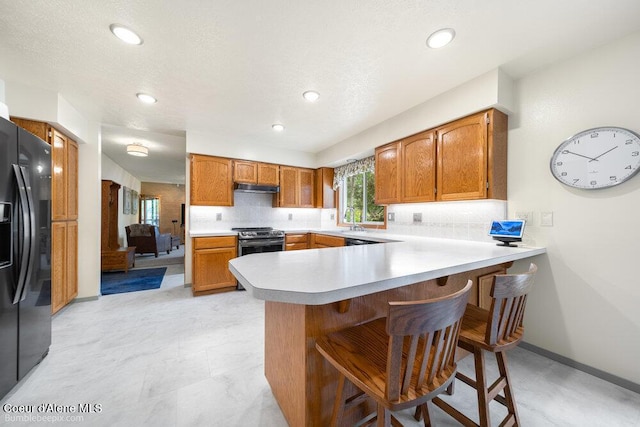 8416 N Haye Ln, Newman Lake, WA 99025 - kitchen featuring black fridge with ice dispenser, stainless steel range, a sink, a peninsula, and under cabinet range hood