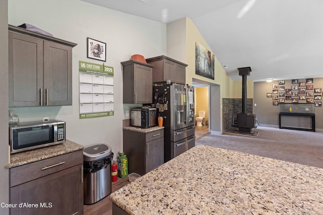53 Koyokuk Trl, Spirit Lake, ID 83869 - kitchen with appliances with stainless steel finishes, a wood stove, open floor plan, dark brown cabinetry, and lofted ceiling