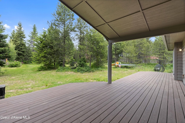 53 Koyokuk Trl, Spirit Lake, ID 83869 - wooden deck featuring a trampoline, a yard, and view of scattered trees