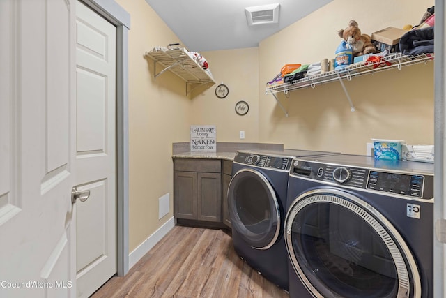 53 Koyokuk Trl, Spirit Lake, ID 83869 - laundry room with washer and clothes dryer, light wood-type flooring, baseboards, and cabinet space