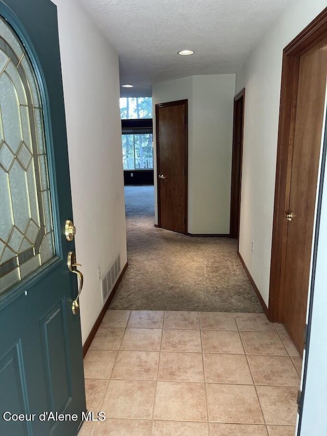 11019 W Crystal Bay Rd, Post Falls, ID 83854 - foyer with light carpet, light tile patterned flooring, baseboards, and a textured ceiling