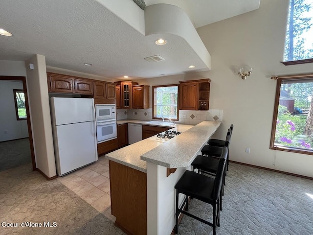 11019 W Crystal Bay Rd, Post Falls, ID 83854 - kitchen with white appliances, light carpet, a peninsula, a sink, and a breakfast bar
