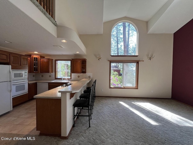11019 W Crystal Bay Rd, Post Falls, ID 83854 - kitchen featuring white appliances, a peninsula, a breakfast bar, light countertops, and a sink