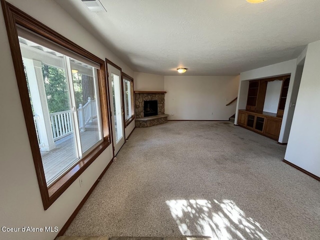 11019 W Crystal Bay Rd, Post Falls, ID 83854 - unfurnished living room featuring light carpet, baseboards, stairs, a textured ceiling, and a stone fireplace