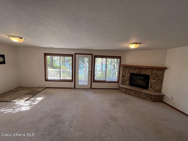 11019 W Crystal Bay Rd, Post Falls, ID 83854 - unfurnished living room featuring plenty of natural light, light colored carpet, a textured ceiling, a stone fireplace, and baseboards