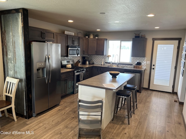 8638 N Spokane St, Post Falls, ID 83854 - kitchen with stainless steel appliances, light wood-type flooring, a breakfast bar, tasteful backsplash, and recessed lighting