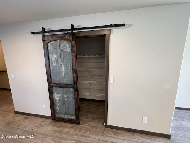 8638 N Spokane St, Post Falls, ID 83854 - unfurnished bedroom featuring wood finished floors, a barn door, and a walk in closet