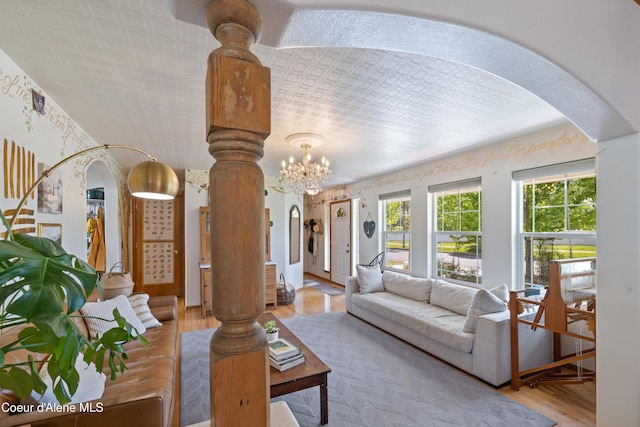 7260 N Courcelles Pkwy, Coeur Dalene, ID 83815 - living area featuring arched walkways, wood finished floors, a chandelier, and decorative columns