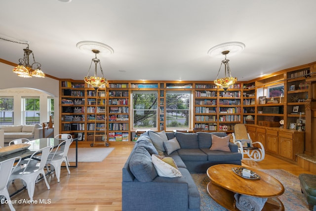 7260 N Courcelles Pkwy, Coeur Dalene, ID 83815 - living room with arched walkways, light wood-type flooring, built in shelves, crown molding, and bookshelves
