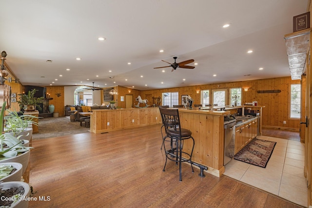 15964 N Songbird Ln, Rathdrum, ID 83858 - kitchen featuring open floor plan, a spacious island, light wood finished floors, wooden walls, and ceiling fan