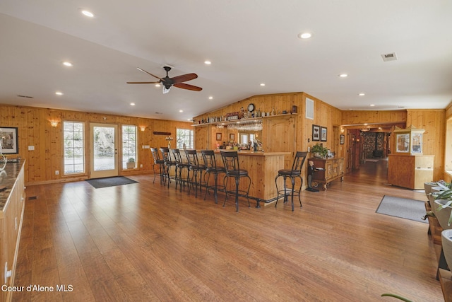 15964 N Songbird Ln, Rathdrum, ID 83858 - kitchen with wood walls, wood finished floors, a ceiling fan, a breakfast bar area, and lofted ceiling