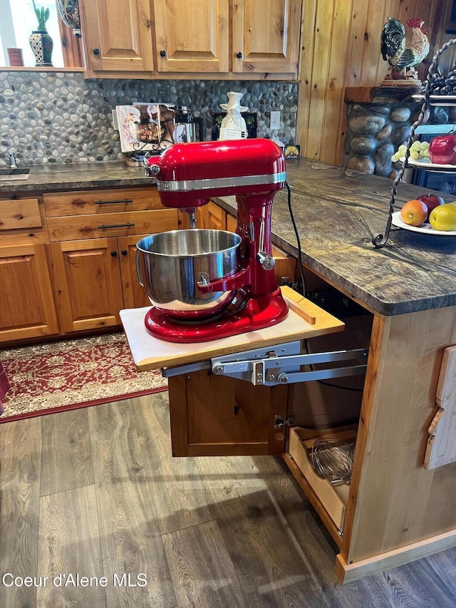 15964 N Songbird Ln, Rathdrum, ID 83858 - kitchen featuring dark wood finished floors, decorative backsplash, dark countertops, brown cabinetry, and wood walls