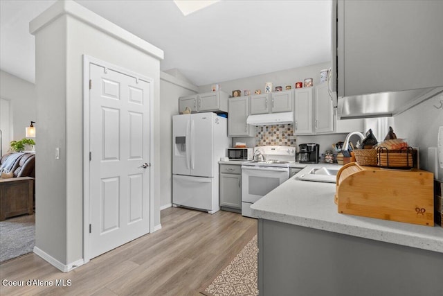 2574 W Sarge Ct, Coeur Dalene, ID 83815 - kitchen featuring white appliances, under cabinet range hood, light wood finished floors, gray cabinets, and vaulted ceiling