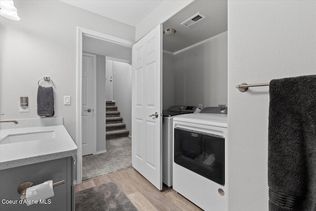 2574 W Sarge Ct, Coeur Dalene, ID 83815 - laundry room with a sink, washer and clothes dryer, and light wood-style flooring