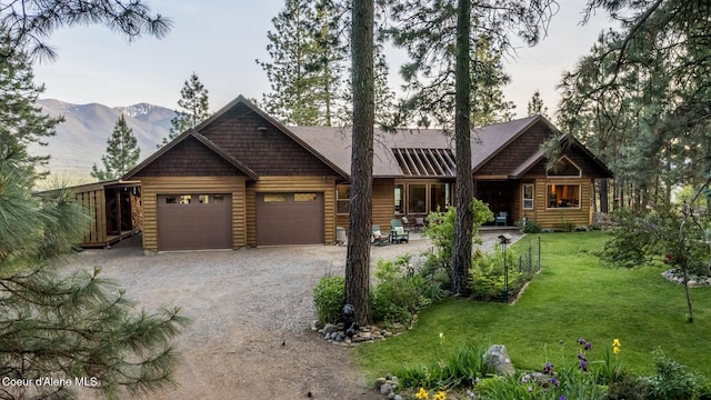 75 Windy Ln, Moyie Springs, ID 83845 - log cabin with driveway, a mountain view, an attached garage, and a front lawn