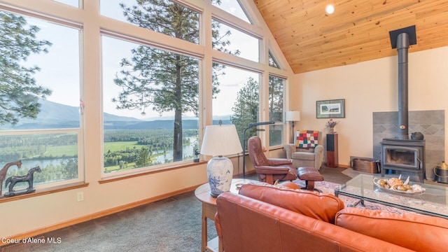 75 Windy Ln, Moyie Springs, ID 83845 - carpeted living room featuring a wood stove, baseboards, a mountain view, plenty of natural light, and wooden ceiling