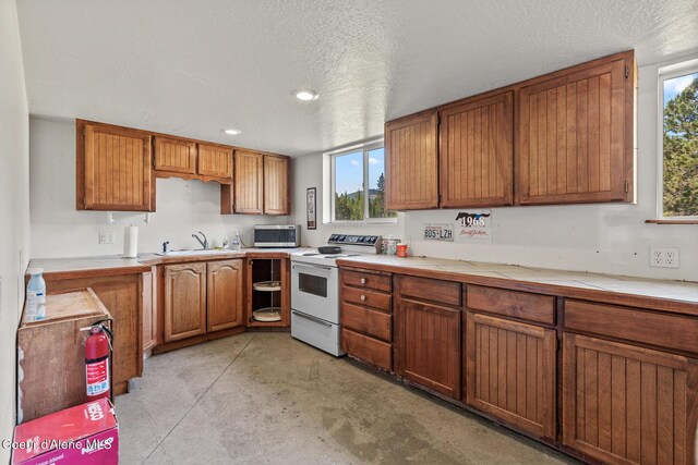 26277 N Chevrolane Way, Rathdrum, ID 83858 - kitchen with white electric range, stainless steel microwave, light countertops, brown cabinetry, and recessed lighting