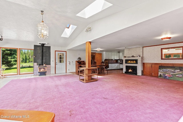 26277 N Chevrolane Way, Rathdrum, ID 83858 - carpeted living area featuring a wood stove, a skylight, wainscoting, a fireplace, and lofted ceiling
