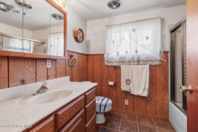 26277 N Chevrolane Way, Rathdrum, ID 83858 - full bathroom featuring vanity, a wainscoted wall, tile patterned flooring, wooden walls, and enclosed tub / shower combo