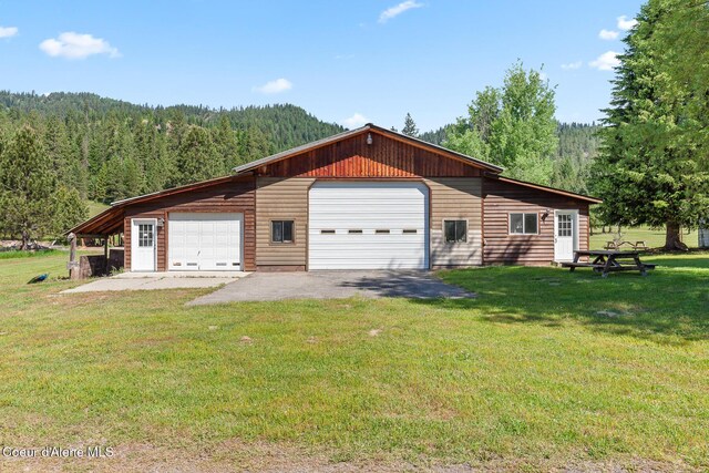 26277 N Chevrolane Way, Rathdrum, ID 83858 - view of side of home with a forest view, a garage, an outbuilding, and a lawn
