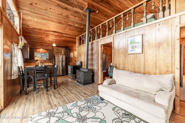 7771 W Channel Ln, Rathdrum, ID 83858 - living area with a wood stove, wood walls, wooden ceiling, light wood-style floors, and vaulted ceiling