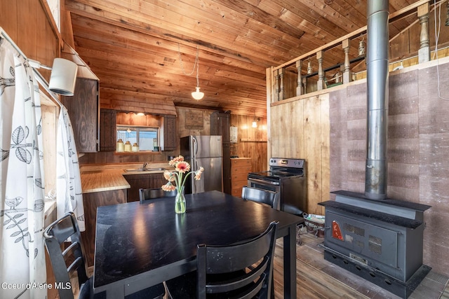 7771 W Channel Ln, Rathdrum, ID 83858 - dining space with wood walls, a wood stove, wooden ceiling, and wood finished floors
