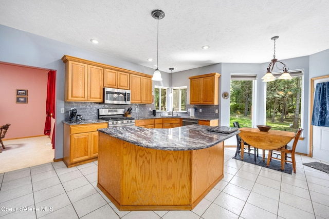 23216 E Morris Rd, Newman Lake, WA 99025 - kitchen with appliances with stainless steel finishes, a sink, backsplash, dark stone counters, and a center island