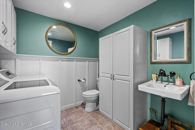 115 Fifth St, Osburn, ID 83849 - half bathroom featuring washer and clothes dryer, toilet, a wainscoted wall, and a decorative wall