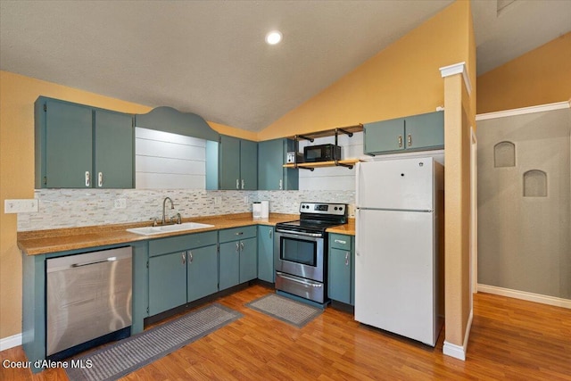115 Fifth St, Osburn, ID 83849 - kitchen with stainless steel appliances, a sink, vaulted ceiling, decorative backsplash, and light wood finished floors